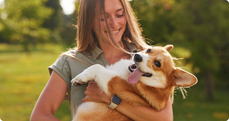 Étudiante tenant un chien souriant dans un parc pour illustrer la licence professionnelle Animal University en médiation, éducation et comportement